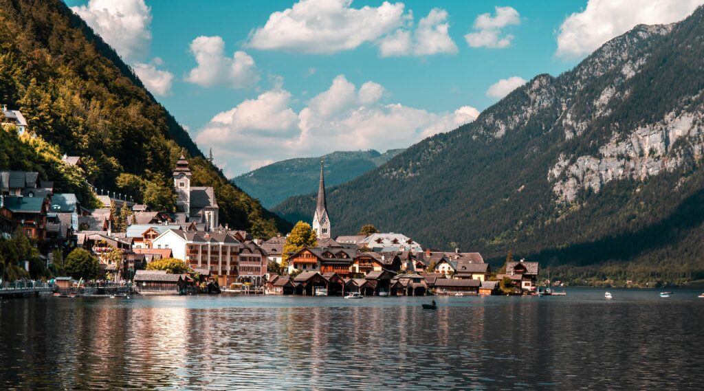 Explore the picturesque town of Hallstatt nestled by a tranquil lake, surrounded by vibrant summer landscapes and majestic mountains.